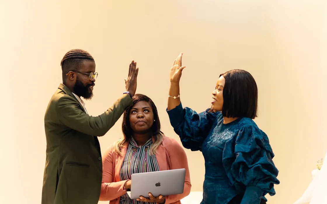 Three colleagues in Lagos celebrating over a laptop